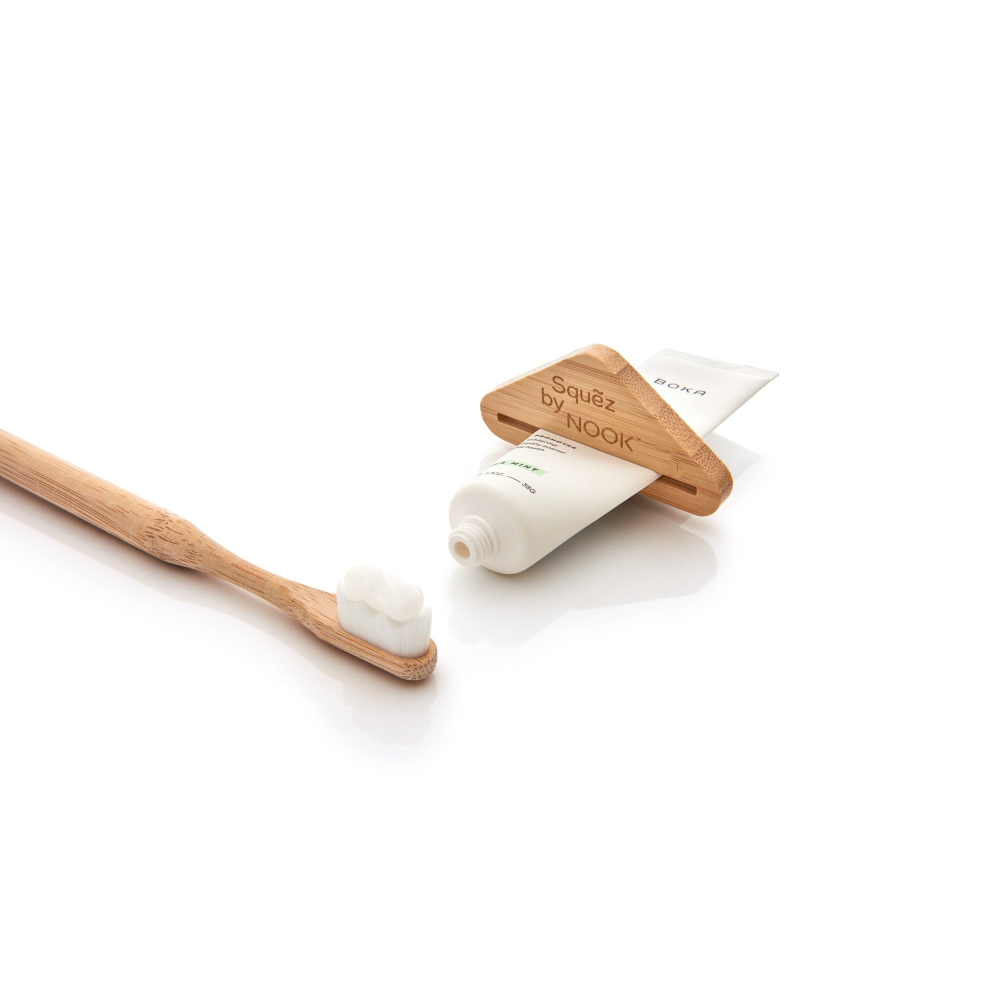 Squẽz by NOOK bamboo toothpaste squeezer dispensing toothpaste onto a bamboo toothbrush